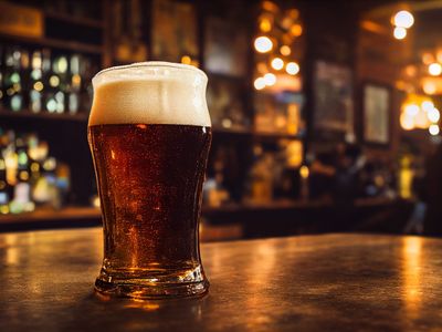 A pint of lager resting on a polished wooden bar counter.